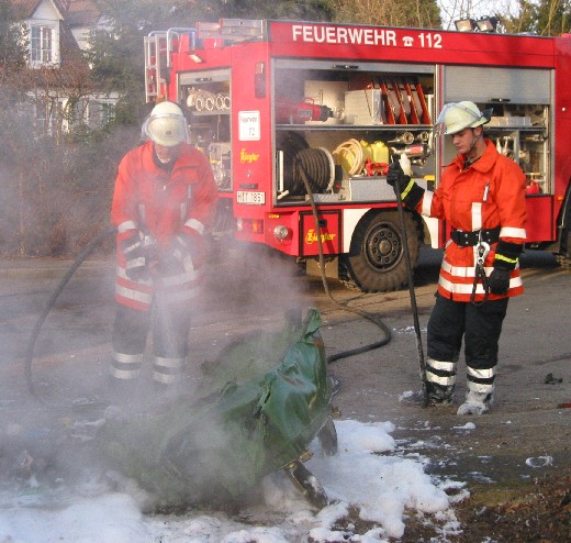 Einsatzkräfte und geschmolzener Müllcontainer